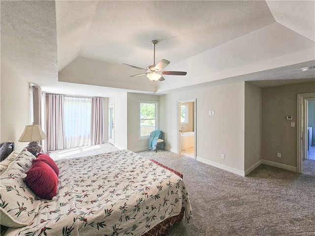 carpeted bedroom featuring a textured ceiling, connected bathroom, a tray ceiling, and ceiling fan