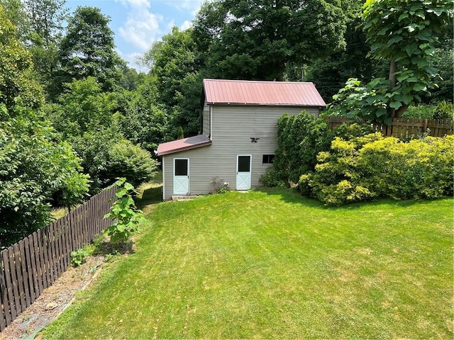 back of property with a yard, metal roof, and fence