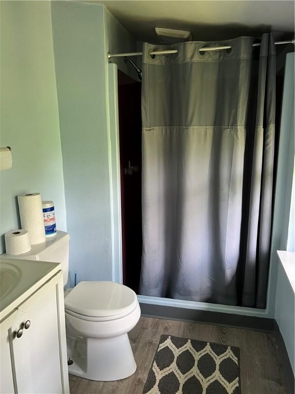bathroom featuring vanity, wood finished floors, a shower with shower curtain, and toilet