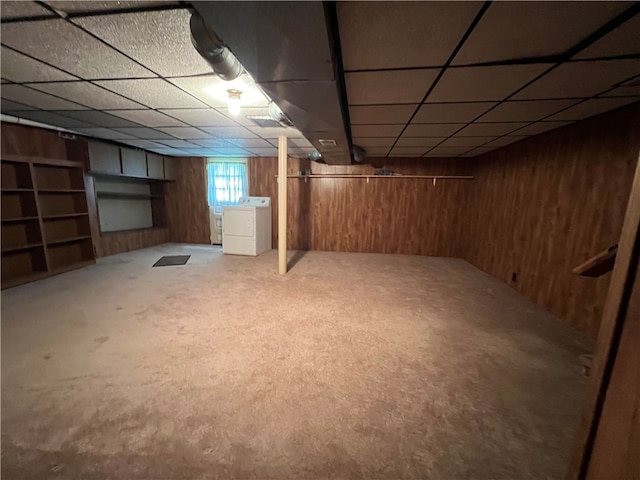 basement with separate washer and dryer, carpet, a paneled ceiling, and wood walls