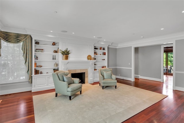 sitting room featuring light hardwood / wood-style floors, ornamental molding, and a tiled fireplace