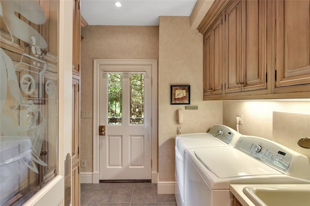 clothes washing area featuring dark tile patterned flooring, washer and dryer, cabinets, and sink