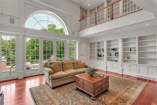 living room with french doors, built in shelves, hardwood / wood-style floors, and a high ceiling