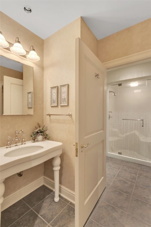 bathroom featuring a shower with door and sink