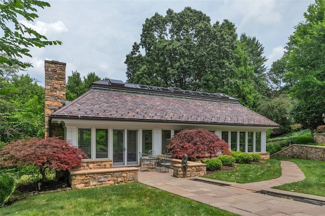 rear view of property with solar panels, a yard, and a patio