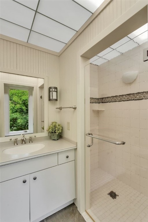 bathroom with vanity, wooden walls, and a shower with shower door