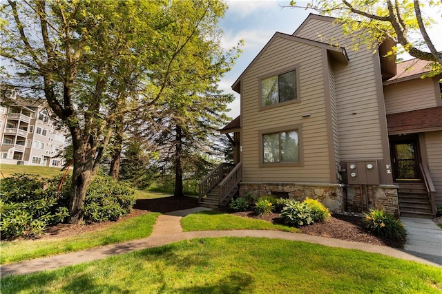 view of front of property featuring stairs, a front yard, and stone siding