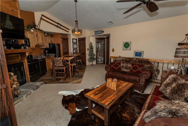 carpeted living room featuring vaulted ceiling, a stone fireplace, ceiling fan, and sink