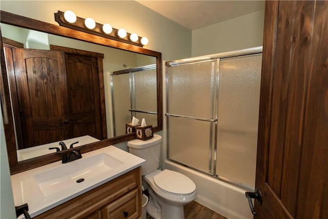 bathroom with enclosed tub / shower combo, toilet, and vanity