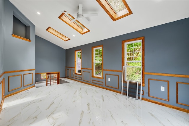 spare room with high vaulted ceiling, light tile flooring, ceiling fan, and a skylight