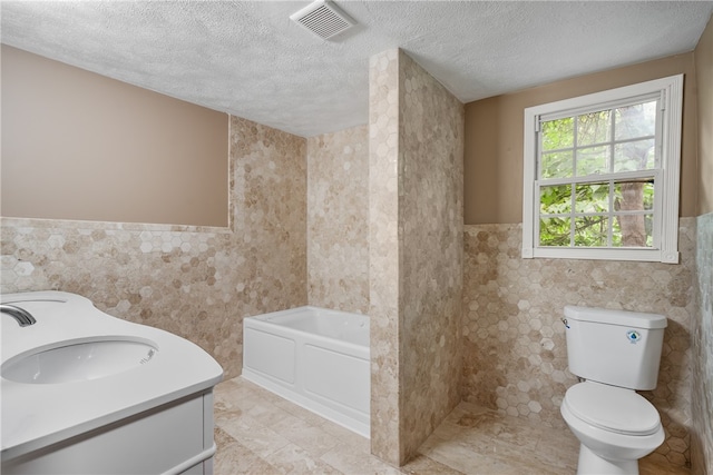 bathroom with tile flooring, a textured ceiling, a washtub, vanity, and toilet