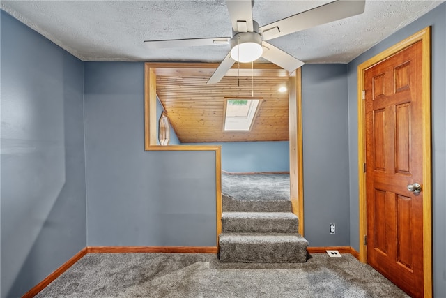 interior space with wood ceiling, a textured ceiling, carpet, and ceiling fan