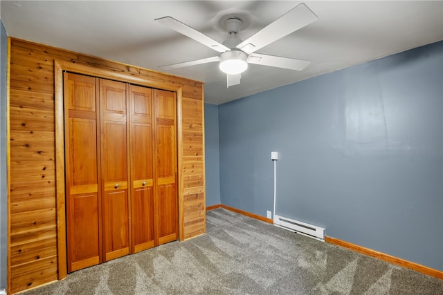 unfurnished bedroom with a baseboard heating unit, carpet, ceiling fan, and a closet