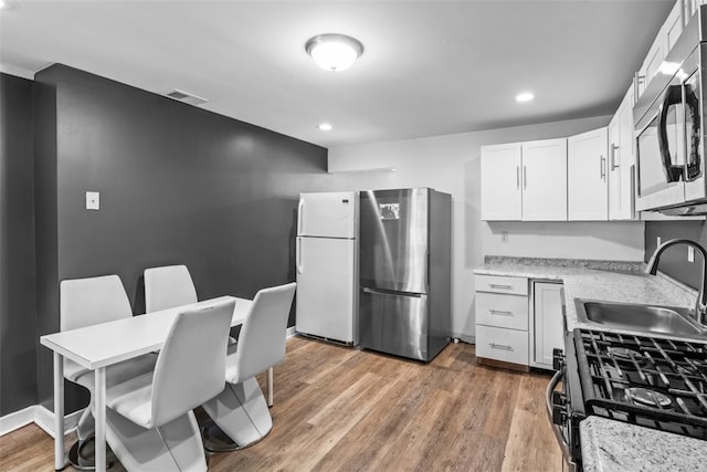 kitchen with white cabinetry, sink, light hardwood / wood-style flooring, and appliances with stainless steel finishes