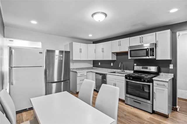 kitchen featuring white cabinetry, appliances with stainless steel finishes, sink, and light hardwood / wood-style flooring