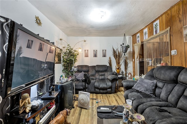 living room with hardwood / wood-style flooring, a textured ceiling, and wood walls