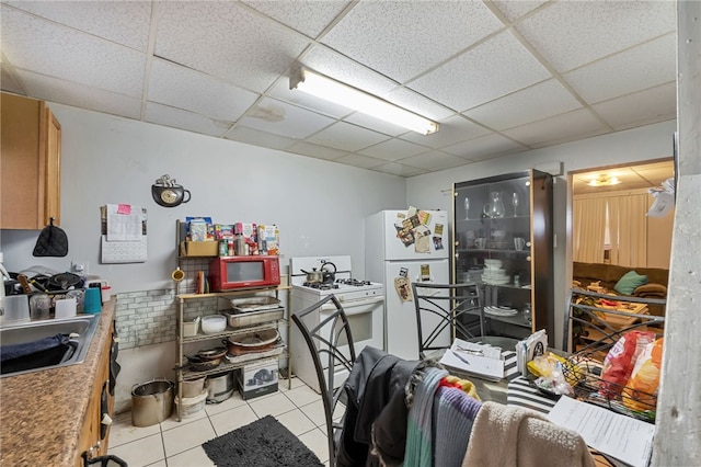 misc room featuring light tile patterned flooring, sink, and a drop ceiling