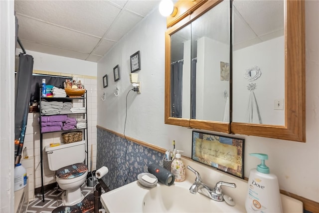 bathroom featuring a shower with curtain, toilet, sink, and a drop ceiling