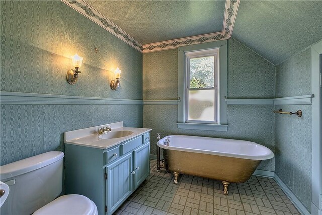 bathroom with a bathing tub, a textured ceiling, lofted ceiling, toilet, and vanity