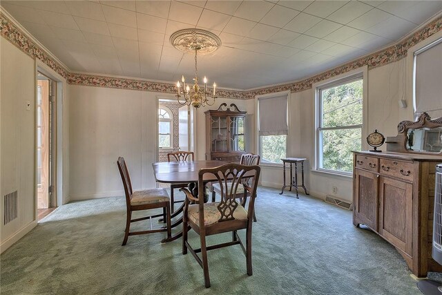 dining space with an inviting chandelier, carpet, and crown molding