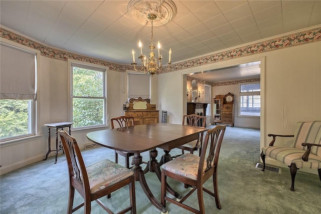 carpeted dining area featuring ornamental molding and a chandelier