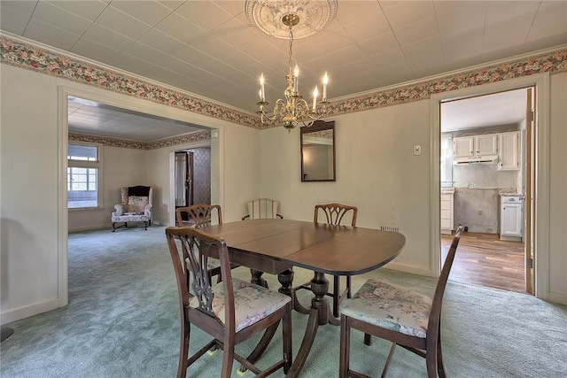 dining area featuring ornamental molding, carpet flooring, and a chandelier