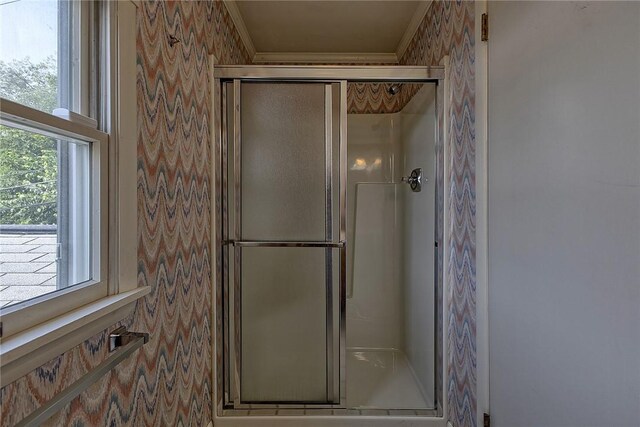 bathroom with crown molding and a shower with door