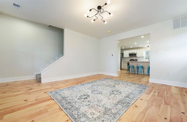 living area with light wood finished floors, visible vents, and stairway