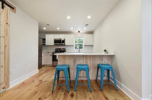 kitchen featuring tasteful backsplash, visible vents, appliances with stainless steel finishes, and a breakfast bar area