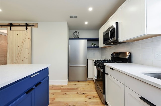 kitchen featuring open shelves, stainless steel appliances, decorative backsplash, and light wood finished floors