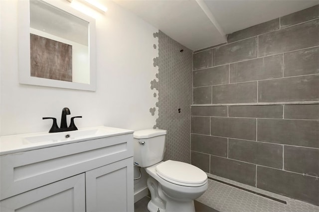 bathroom featuring a tile shower, vanity, and toilet