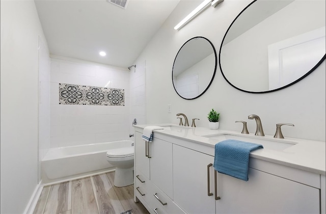 full bathroom with toilet, double vanity, bathing tub / shower combination, wood finished floors, and a sink