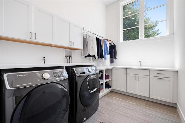 washroom with washing machine and clothes dryer, sink, and cabinets