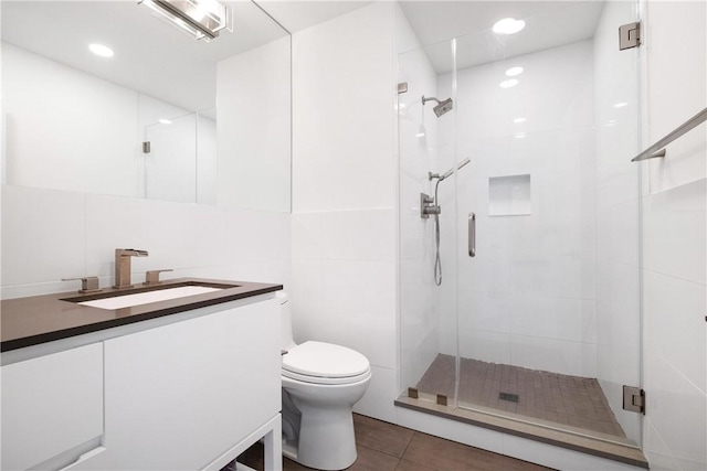 bathroom featuring tile patterned flooring, an enclosed shower, toilet, vanity, and tile walls