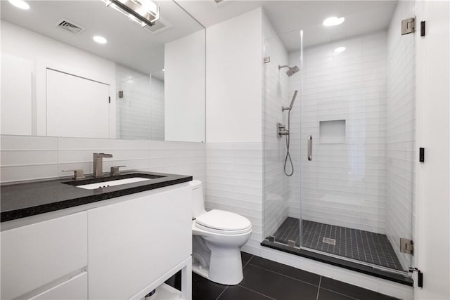 bathroom featuring tile patterned floors, vanity, a shower with shower door, and toilet