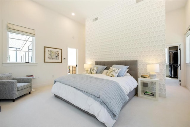 carpeted bedroom with a walk in closet and a towering ceiling