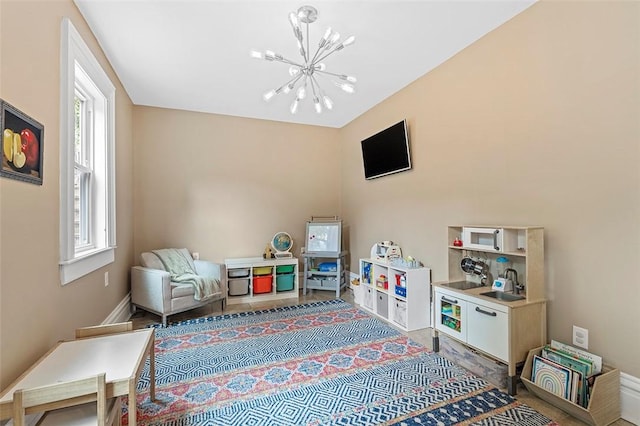 playroom featuring hardwood / wood-style floors, an inviting chandelier, and a healthy amount of sunlight