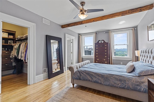 bedroom with a walk in closet, ceiling fan, a closet, and light hardwood / wood-style floors