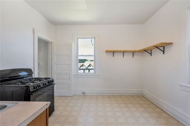 kitchen featuring black gas range oven and light tile floors