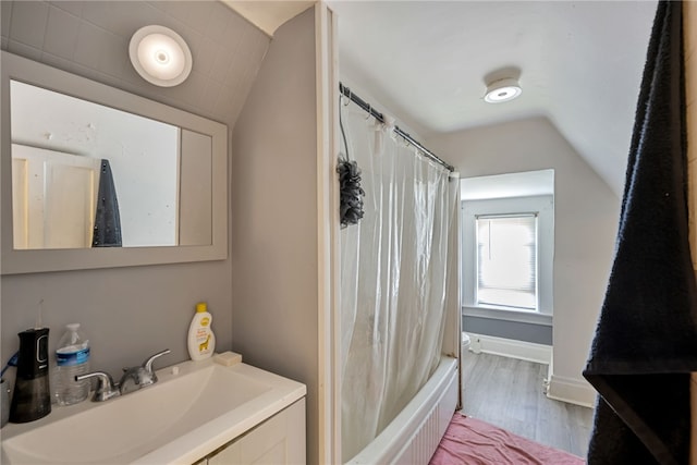 bathroom featuring vaulted ceiling, oversized vanity, shower / bath combo with shower curtain, and wood-type flooring