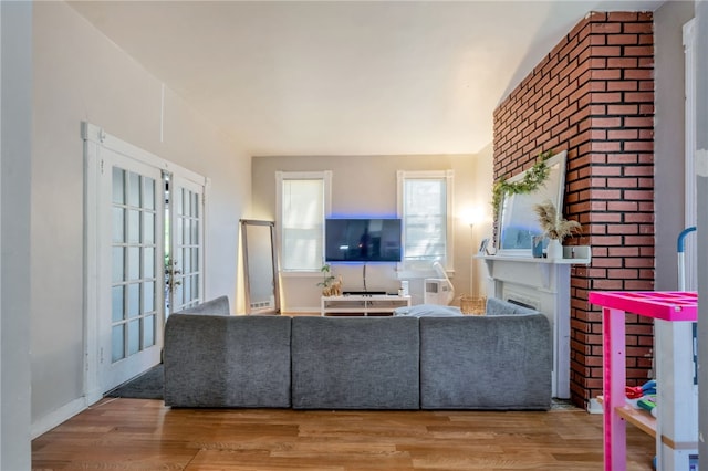 living room featuring a brick fireplace, wood-type flooring, and french doors