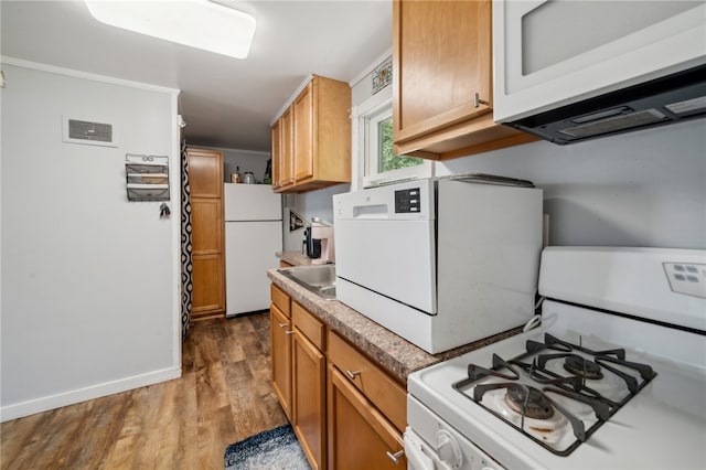 kitchen with wood-type flooring, sink, ornamental molding, and white appliances