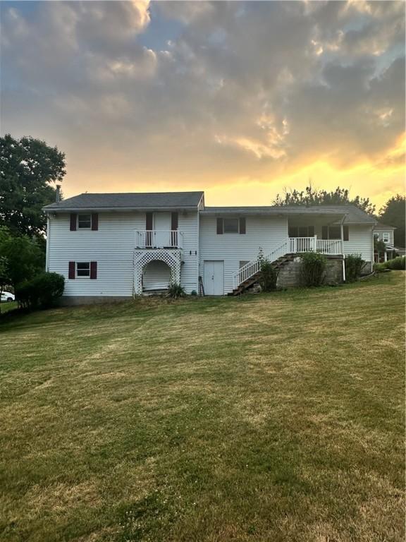 back house at dusk featuring a lawn