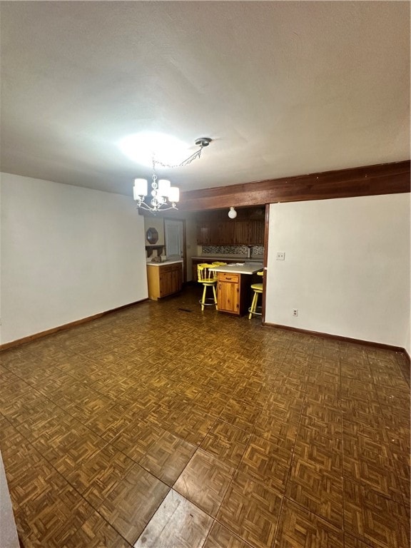 spare room featuring dark parquet floors and an inviting chandelier