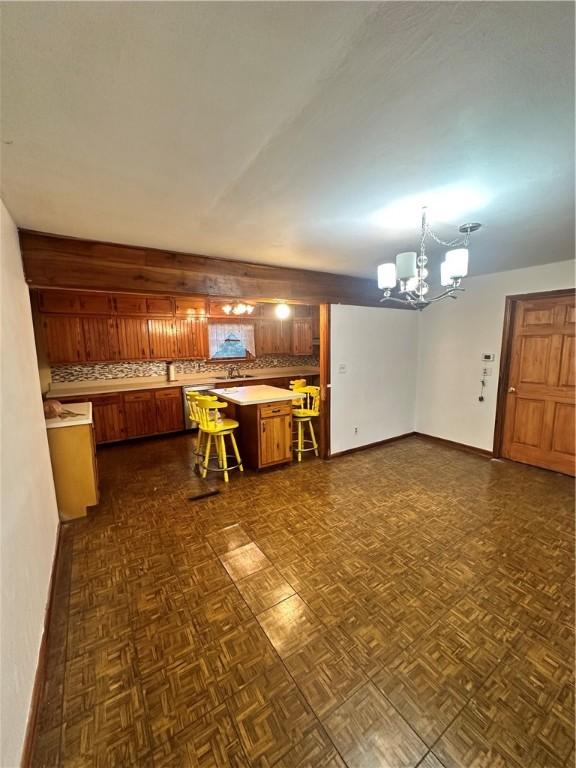 kitchen featuring dark parquet flooring, a notable chandelier, sink, and pendant lighting