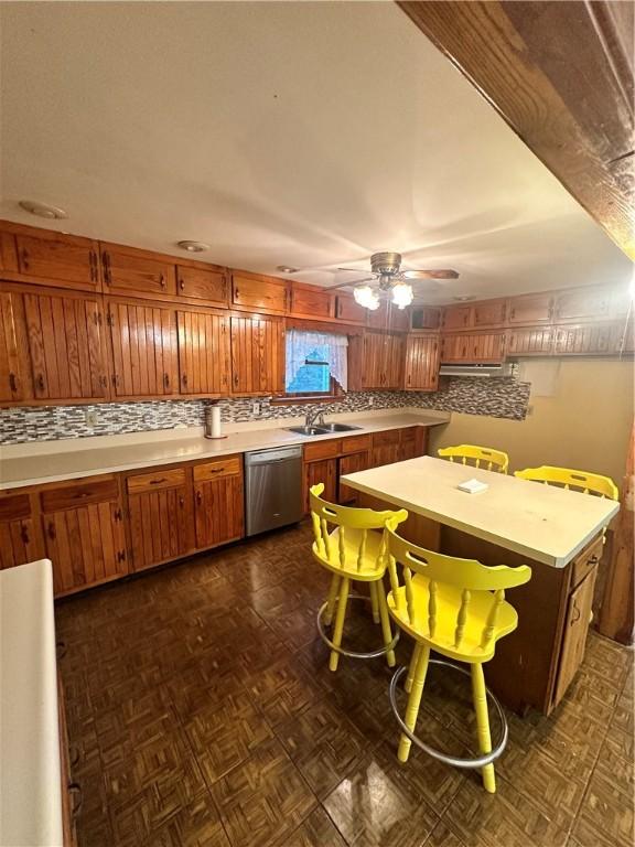 kitchen with dark parquet floors, stainless steel dishwasher, backsplash, sink, and ceiling fan