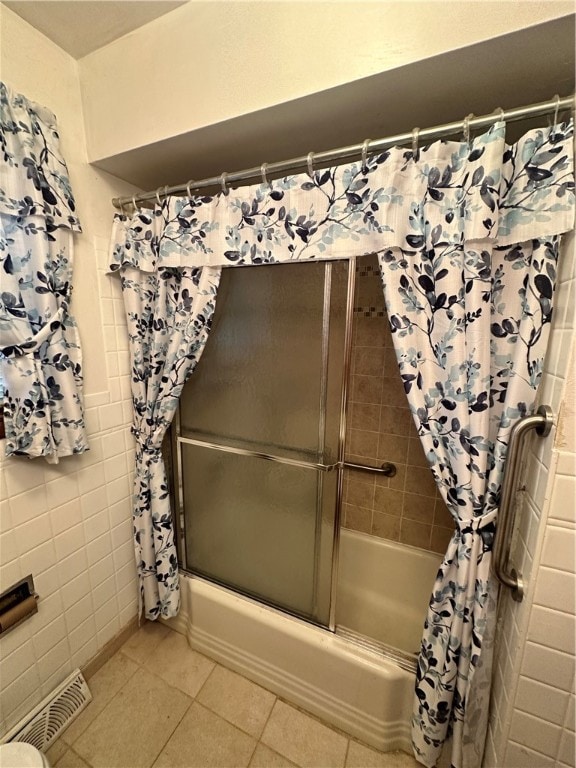 bathroom featuring tile walls, tile floors, and bath / shower combo with glass door