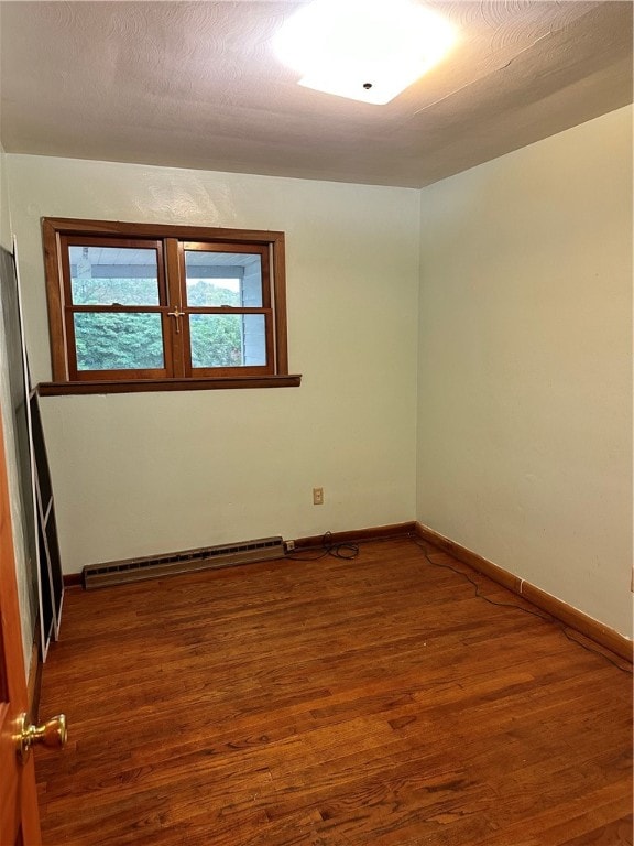 empty room with a baseboard heating unit and dark wood-type flooring