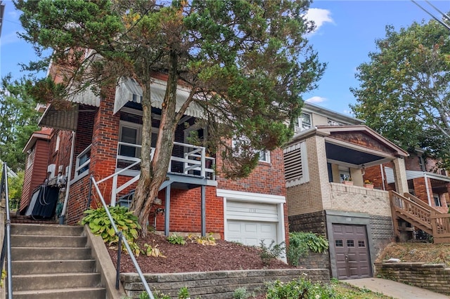 view of front of property featuring brick siding, an attached garage, and stairs