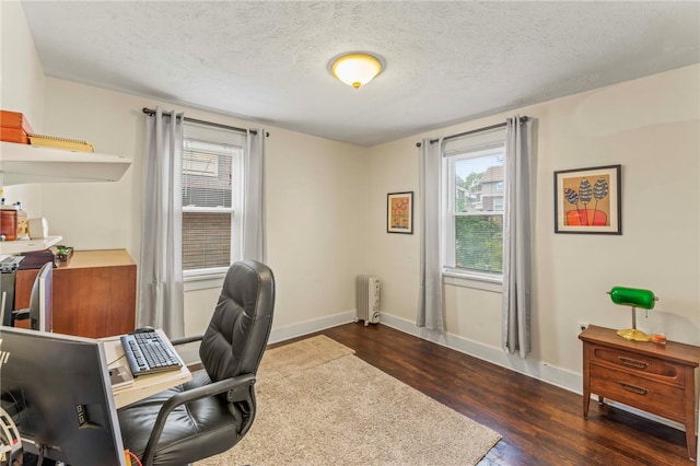 office featuring a textured ceiling, dark hardwood / wood-style floors, and radiator heating unit